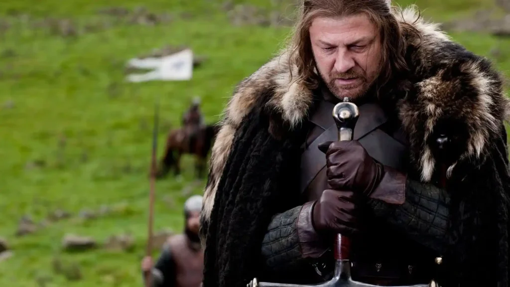 Sean Bean interpreta Ned Stark, com espada em mãos e expressão séria, em cena de Game of Thrones.