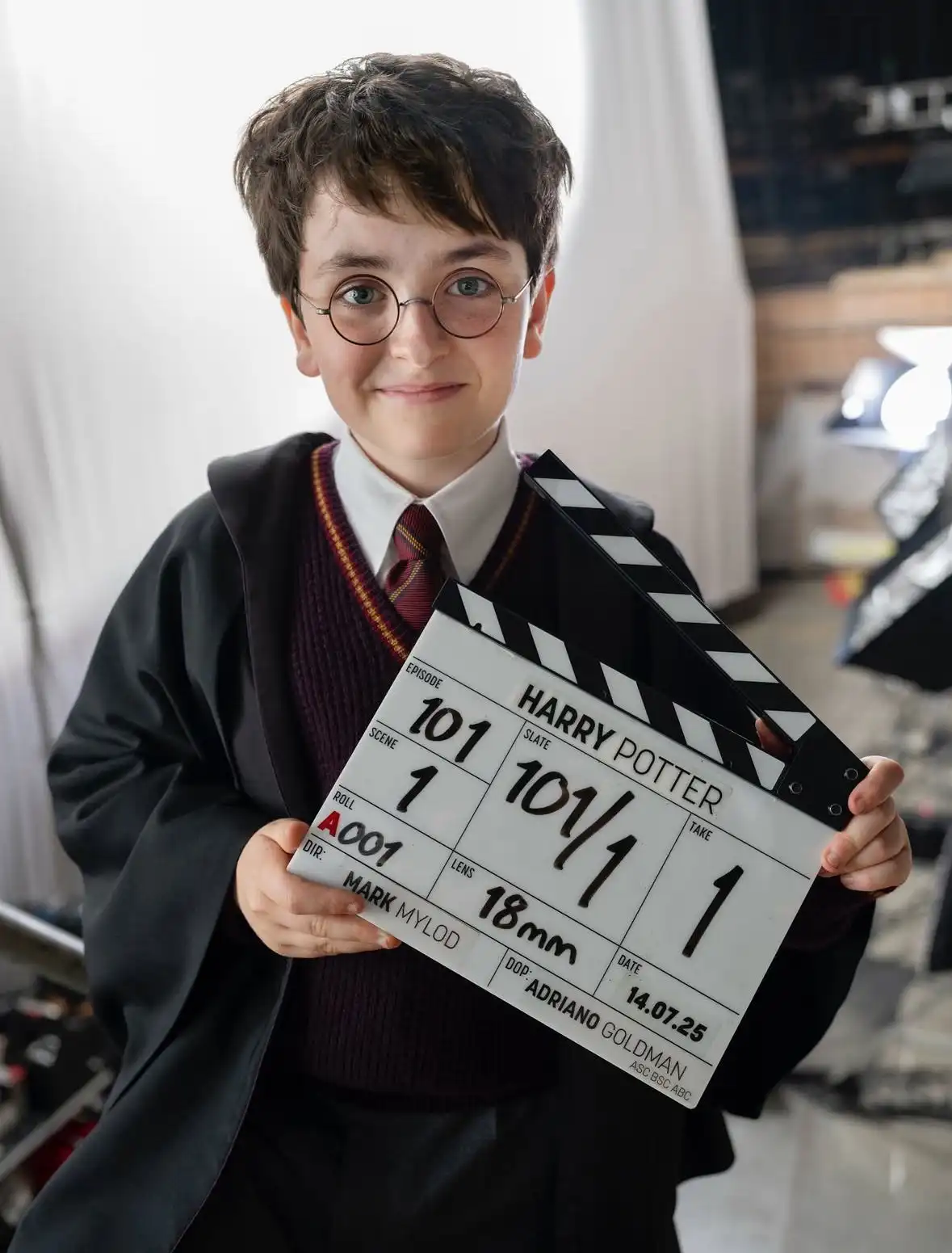Dominic McLaughlin caracterizado como Harry Potter, con uniforme de Gryffindor y claqueta anunciando inicio del rodaje de la serie