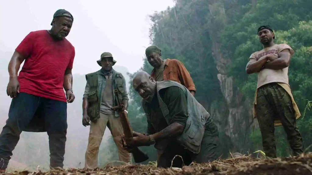 Five Vietnam War veterans in jungle clearing examining an object with tense atmosphere