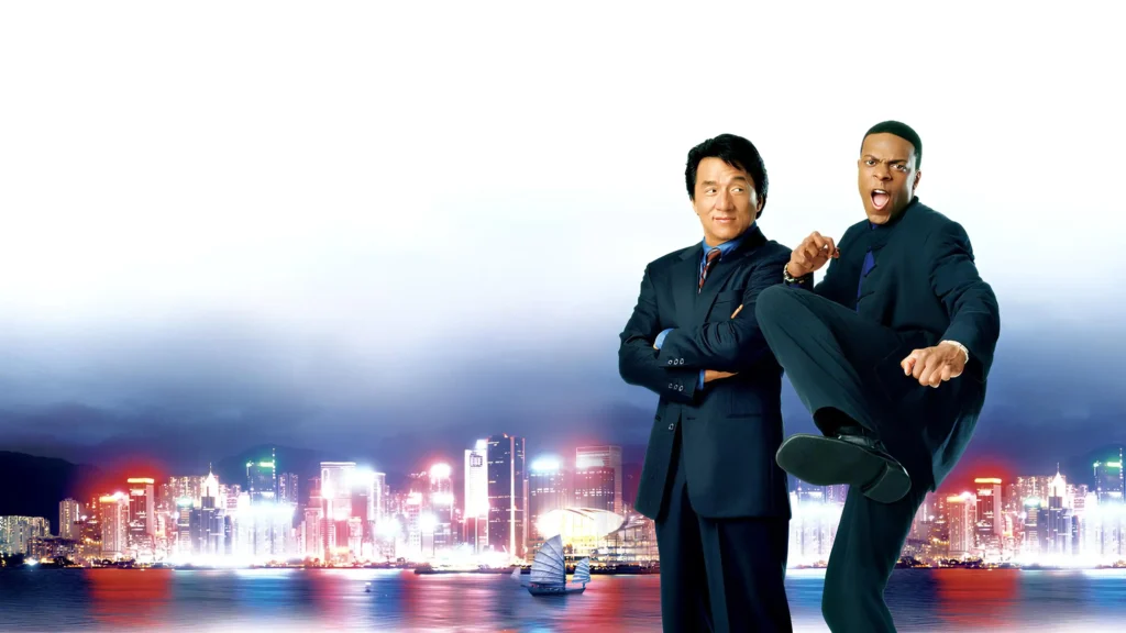Two men in dark suits posing together against Hong Kong city skyline at night, one Asian man with arms crossed and one Black man in dynamic martial arts stance.