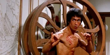 Escena de acción de la película Operación Dragón (1973) con Bruce Lee en posición de combate, mostrando su característica intensidad y destreza en artes marciales, probablemente enfrentando a uno de los secuaces de Han en la isla donde se desarrolla el torneo secreto de kung fu.
(Credits: TMDB)