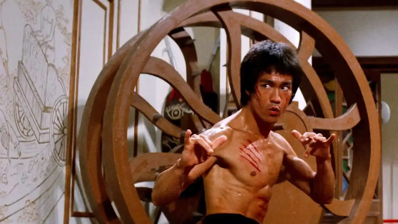 Escena de acción de la película Operación Dragón (1973) con Bruce Lee en posición de combate, mostrando su característica intensidad y destreza en artes marciales, probablemente enfrentando a uno de los secuaces de Han en la isla donde se desarrolla el torneo secreto de kung fu.
(Credits: TMDB)